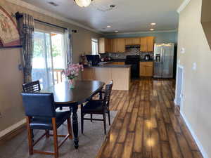 Dining space featuring dark hardwood / wood-style floors, an inviting chandelier, crown molding, and sink