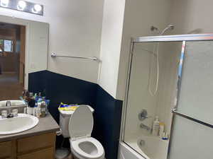 Full bathroom with shower / bath combination with glass door, vanity, and toilet