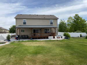 Rear view of property with a lawn, a deck, and a patio