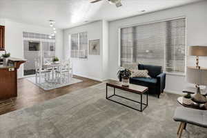 Carpeted living room featuring ceiling fan and a textured ceiling