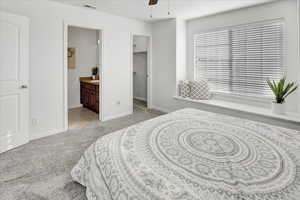 Carpeted bedroom featuring connected bathroom, a spacious closet, and ceiling fan