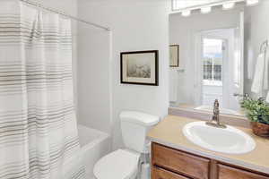 Full bathroom featuring toilet, vanity, and shower / tub combo.