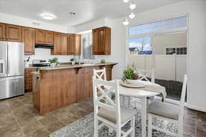 Kitchen featuring a textured ceiling, kitchen peninsula, a breakfast bar area, and appliances with stainless steel finishes