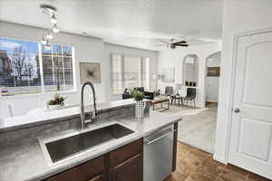 Kitchen featuring ceiling fan, dishwasher, sink, and a textured ceiling