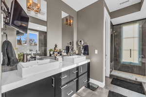 Bathroom featuring tile patterned floors, a notable chandelier, a tile shower, and vanity