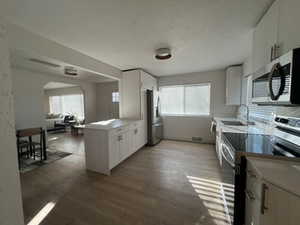 Kitchen featuring white cabinets, stainless steel appliances, a wealth of natural light, and hardwood / wood-style floors