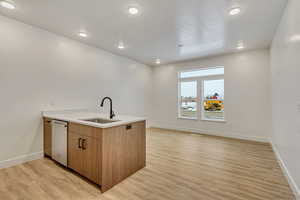 Kitchen featuring sink, kitchen peninsula, white dishwasher, a textured ceiling, and light wood-type flooring