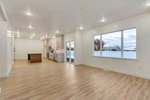 Unfurnished living room with light hardwood / wood-style flooring, a healthy amount of sunlight, and sink