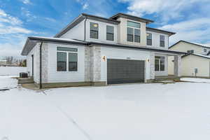 View of front of home featuring a garage and central air condition unit