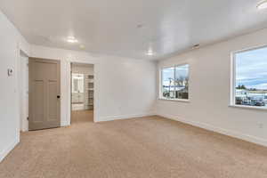 Empty room with light colored carpet and a textured ceiling