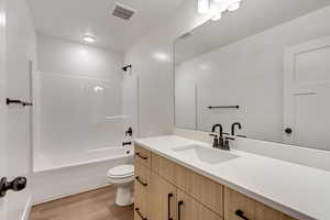 Full bathroom with vanity, shower / bathtub combination, toilet, and wood-type flooring