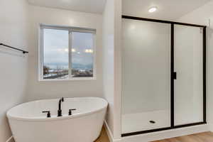 Bathroom featuring wood-type flooring and shower with separate bathtub