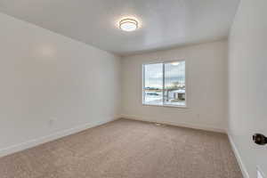 Carpeted empty room featuring a textured ceiling