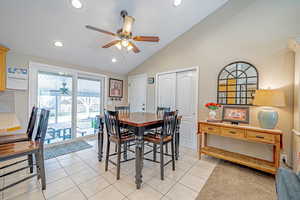 Tiled dining area with ceiling fan and lofted ceiling