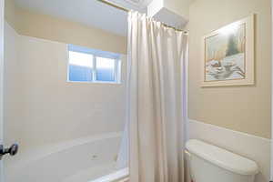 Bathroom with toilet, a textured ceiling, and shower / tub combo