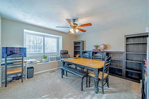 Office area with a textured ceiling, carpet floors, and ceiling fan