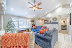 Tiled living room featuring ceiling fan, beam ceiling, and high vaulted ceiling