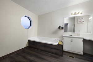 Bathroom with a bathtub, hardwood / wood-style floors, vanity, and a textured ceiling