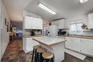 Kitchen with white cabinetry, a center island, white appliances, and sink