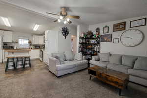 Living room featuring carpet flooring, ceiling fan, sink, and a textured ceiling