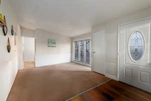 Entrance foyer with dark hardwood / wood-style flooring and a textured ceiling