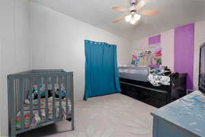 Bedroom featuring carpet, a textured ceiling, a crib, and ceiling fan