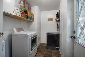 Clothes washing area featuring cabinets, a textured ceiling, and washer and clothes dryer