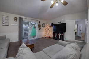 Living room featuring a textured ceiling, ceiling fan, carpet, and vaulted ceiling