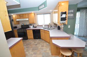 Kitchen featuring a breakfast bar area, kitchen peninsula, sink, and black appliances