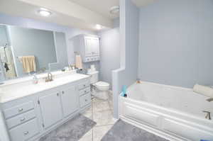 Bathroom with a washtub, vanity, tile patterned floors, and toilet