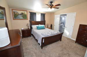 Carpeted bedroom featuring connected bathroom, ceiling fan, and lofted ceiling