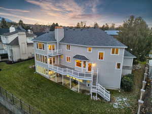 Back house at dusk featuring a lawn and a balcony