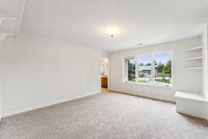 Freshly painted and carpeted bedroom with large windows, storage seat, built in shelves and desk