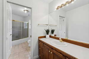 Full bathroom featuring tile patterned floors, toilet, vanity, and combined bath / shower with glass door