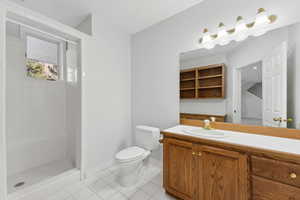 Bathroom with tile patterned floors, vanity, toilet, and tiled shower