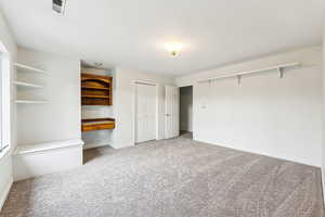 Freshly painted and carpeted bedroom with large windows, storage seat, built in shelves and desk