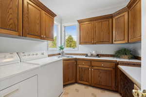 Main floor laundry room with cabinets, independent washer and dryer, sink and golf course and mountain views