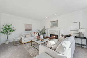 Freshly carpeted and painted living room with a tile fireplace and ornamental molding