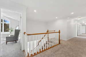 Stairs from main level entry to second level hallway featuring light carpet and ornamental molding