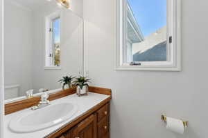 Main floor half bath with vanity, toilet, and ornamental molding