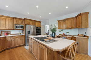 Kitchen with a kitchen island, crown molding, light hardwood / wood-style floors, and stainless steel appliances