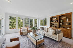 Freshly carpeted and painted family room with floor to ceiling windows, walk out to deck, stone fireplace and built ins.