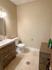 Bathroom with tile patterned flooring, vanity, a drop ceiling, and toilet