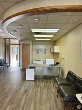 Office area with a paneled ceiling and dark wood-type flooring