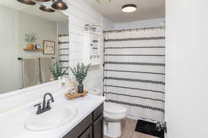 Bathroom with vanity, hardwood / wood-style flooring, toilet, and wooden walls