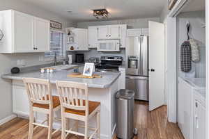 Kitchen featuring sink, separate washer and dryer, kitchen peninsula, and appliances with stainless steel finishes