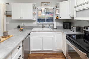 Kitchen featuring dark hardwood / wood-style floors, sink, white cabinetry, and stainless steel appliances