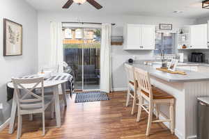 Kitchen featuring a kitchen breakfast bar, ceiling fan, white cabinets, and wood-type flooring