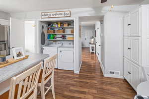 Laundry room featuring a textured ceiling, dark hardwood / wood-style floors, ceiling fan, and washing machine and clothes dryer