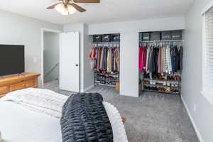 Carpeted bedroom featuring multiple closets, ceiling fan, and a textured ceiling